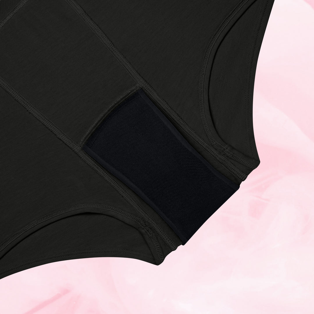 To sorte Teens Boxer Moderat Flow menstruationstrusser på lyserød baggrund.