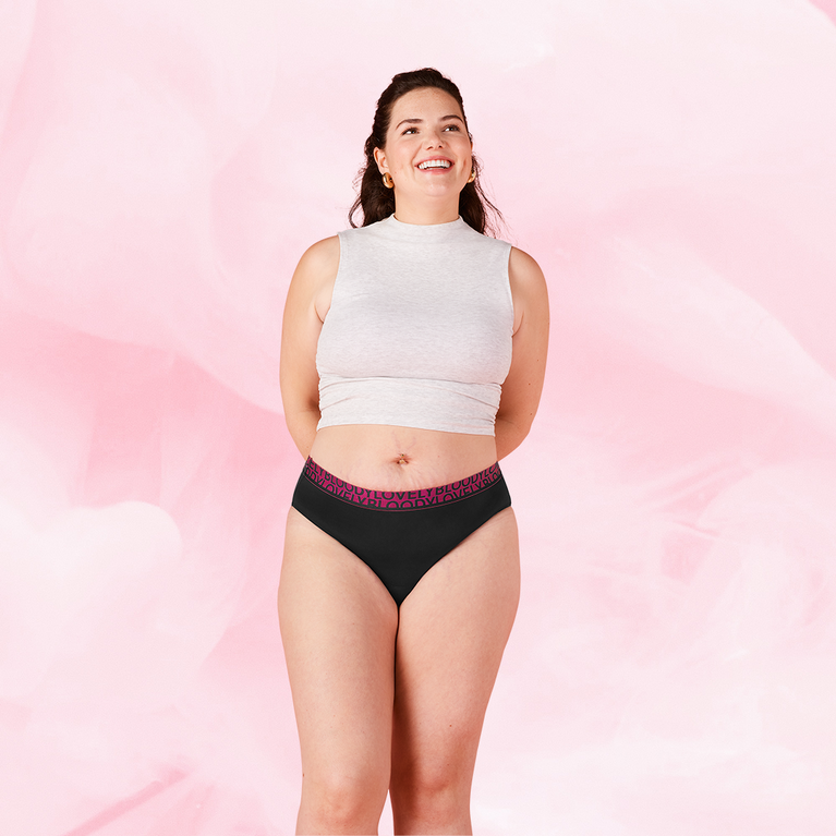 Person iført ComfortFit High Leg Riklig Flow menstruationstrusser, smilende og afslappet.