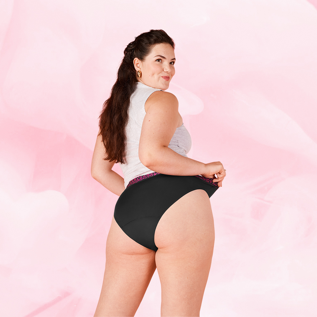 Kvinde iført ComfortFit High Leg Måttlig Flow menstruationstrusser, viser mønstret linning.